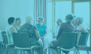 QIP blue image of a circle of older ladies sitting in a circle chatting and laughing